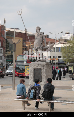 Drei junge Männer sitzen auf einer Bank vor der Statue von Neptun im zentralen Bristol, UK. Stockfoto