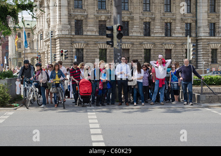 Fußgänger, die darauf warten, überqueren Sie eine Straße in München, Deutschland Stockfoto