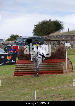 Pferd und Reiter löschen einen Zaun auf der Langlaufloipe auf dem britischen Festival der Vielseitigkeit in Gatcombe Park in Gloucestershire Stockfoto