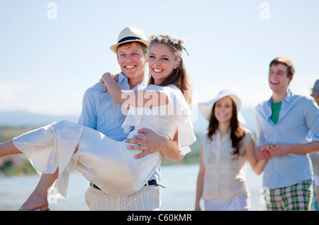 Bräutigam trägt Braut im freien Stockfoto