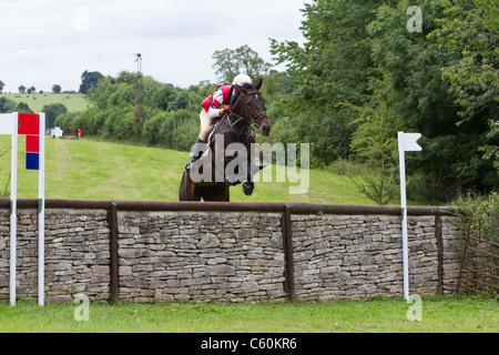 Pferd und Reiter Löschen einer Wand auf der Langlaufloipe auf dem britischen Festival der Vielseitigkeit in Gatcombe Park in Gloucestershire Stockfoto