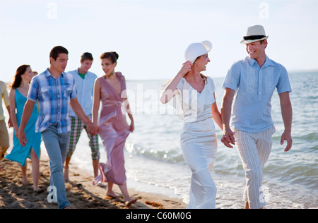 Frisch vermählte Paar am Strand mit Freunden Stockfoto