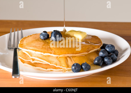 Heidelbeer-Pfannkuchen auf einem Teller mit der Gabel auf einem Holztisch Stockfoto