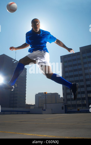 Mann Prellen Fußball auf dem Kopf Stockfoto