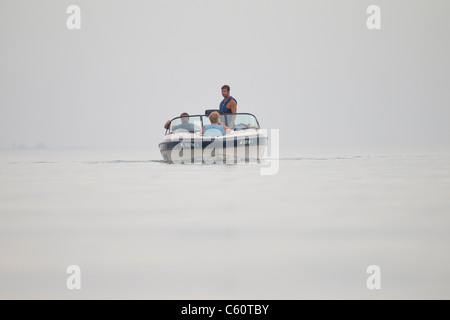 Ein Boot mit einer Familie an einem nebligen Morgen nähert. Stockfoto