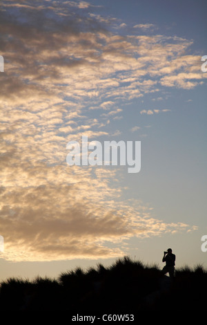 Man fotografiert den dramatischen Himmel Silhouette auf den Grasbüscheln auf einem Hügel am Studland, Dorset im August Stockfoto