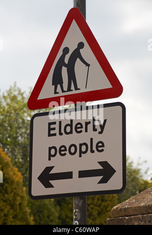 Ältere Menschen überqueren Straßenschild in den Cotswolds, Gloucestershire, Großbritannien im Juli - dreieckige Straßenschild Dreieck Stockfoto