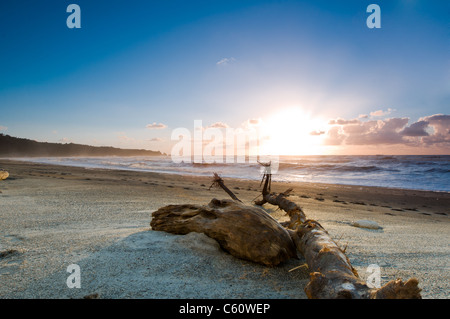 Sonnenuntergang über einem nebligen Strand mit brennenden Himmel Stockfoto