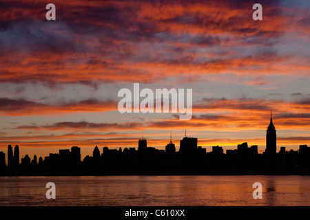 Der Himmel beginnt zu erleichtern und Wolken reflektieren vor Sonnenaufgang Farbe über die Skyline von Midtown Manhattan in New York City. Stockfoto