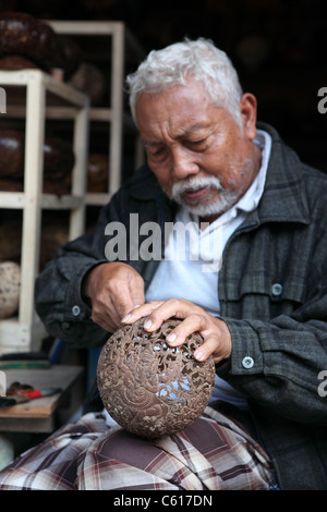 Handwerker, schnitzen eine getrocknete Kokosnuss-Schale. Tampaksiring, Bali, Indonesien, Südostasien, Asien Stockfoto