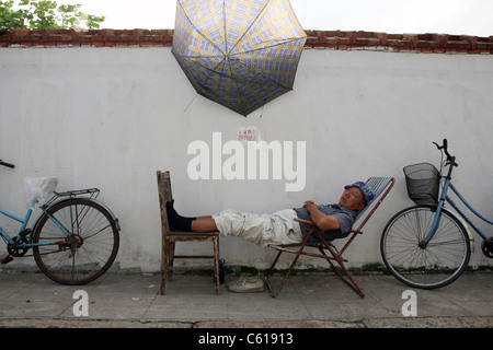 Ein älterer Mann nimmt ein Nickerchen unter einem Regenschirm in der alten Stadt-Distrikt von Shanghai am 16. September 2008. Stockfoto