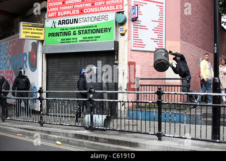 Maskierte Jugendliche werfen einen Lagerplatz bei der Bereitschaftspolizei in Straßenschlachten in Hackney, London Stockfoto