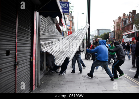 Plünderer mit Gewalt ihren Weg in ein Geschäft in Hackney Straße Krawalle, London. Stockfoto