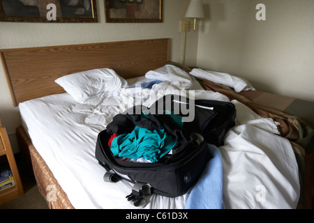 Single mans Reise Koffer mit Bündel von Kleidung auf günstiges Hotel Motelzimmer in den usa Stockfoto