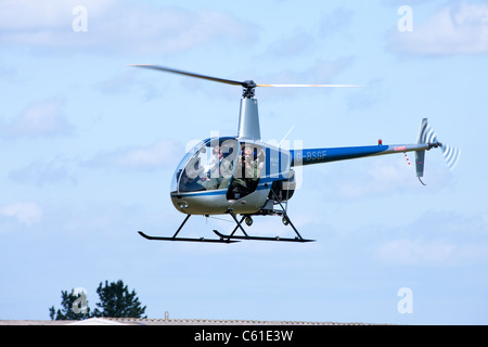 Robinson r-22 Beta-G-BSGF im Flug mit dem Fotografen fotografieren Stockfoto