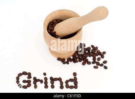 Nahaufnahme der Kaffeebohnen von Hand mit Mörtel und Pestal. Das Wort Grind wird mit Kaffeebohnen geschrieben. Stockfoto
