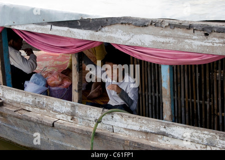 Asiatische Junge sitzt in einem alten bewaldeten Fähre Boot auf dem Mekong in Kambodscha. Stockfoto