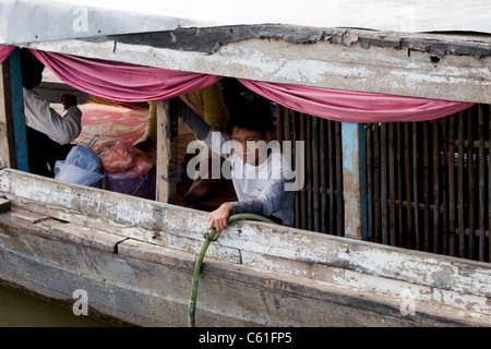 Asiatische Junge sitzt in einem alten bewaldeten Fähre Boot auf dem Mekong in Kambodscha. Stockfoto