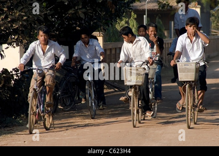 Eine Gruppe von Jungs im Teenageralter sind Reiten Fahrräder von der Schule auf einer unbefestigten Straße in Kampong Cham Provinz, Kambodscha. Stockfoto