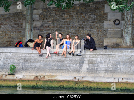Fünf Frauen und ein Fotograf sitzen am Ufer der Seine, Paris Stockfoto