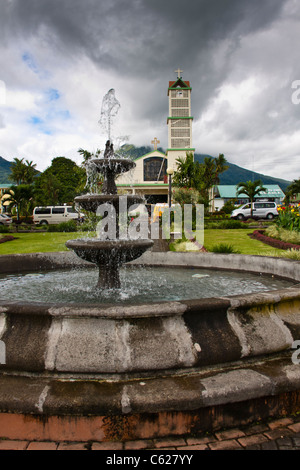 Stadtpark und katholische Kirche in La Fortuna, Costa Rica, mit Arenal Vulkan im Hintergrund. Stockfoto