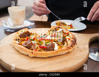 Mann isst ein Stück frisch zubereitete Pizza in einem Café. Stockfoto