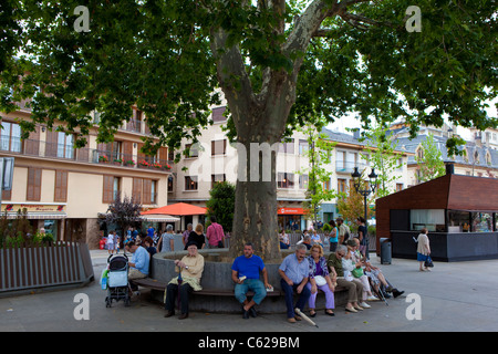 Leute sitzen unter einem Baum im Placa de Santa Maria, Puigcerda, Sonntagmorgen, August 2011 Stockfoto