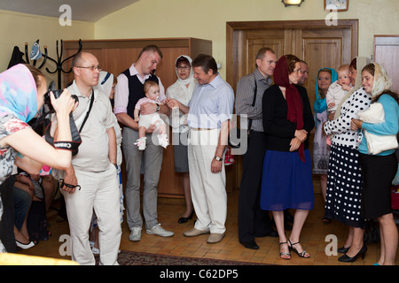 Taufe eines kleinen Kindes in eine christliche Russisch-orthodoxe Kirche. Menschen mit Kindern im Zimmer vor einer Taufe. Stockfoto