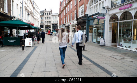 Ein junges Paar von hinten entlang vorbei an Geschäften und Boutiquen in der New Bond Street in London W1 England UK KATHY DEWITT gesehen Stockfoto