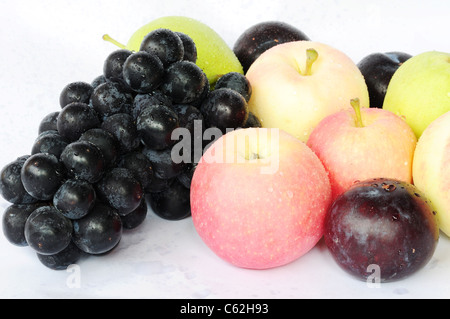 Frischen Weintrauben, Äpfel, Birnen und Pflaumen mit Wassertropfen auf einem weißen Hintergrund Stockfoto