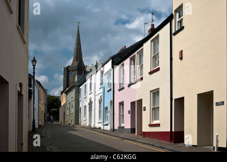 Tenby, eine Reihe von bunten Reihenhäuser mit ein Kirchturm im Hintergrund, Pembrokeshire, South Wales, Großbritannien Stockfoto