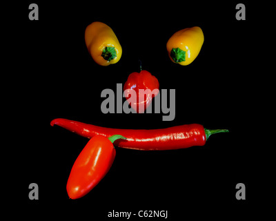 Lustiges Gesicht von Paprika und Chili auf schwarzen Hintergrund gemacht. Stockfoto