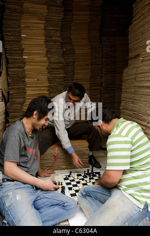 Drei iranische Männer spielen Schach in einem Lager oder Lager während der Pausen in der Innenstadt von Teheran, Iran. Stockfoto