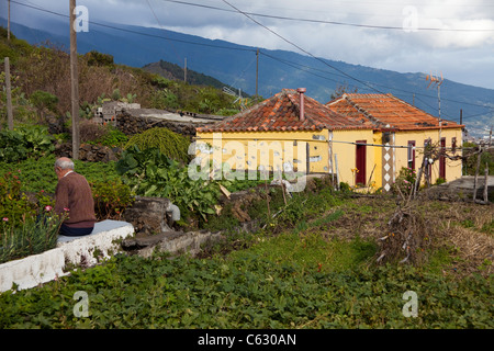 Alte Mann sitzt auf einem Garten Wand, typisch kleines Haus in Mazo, La Palma, Kanarische Inseln, Spanien, Europa Stockfoto