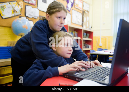 Zwei Schulmädchen mit einem Laptop in einem Klassenzimmer im Vereinigten Königreich Stockfoto