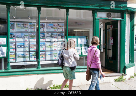 Zwei Frauen, die Eigenschaften im Fenster eines Immobilienmaklers ausgeschrieben. Die Frauen sind eine Mutter und Tochter. Stockfoto
