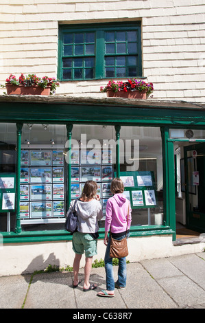 Zwei Frauen, die Eigenschaften im Fenster eines Immobilienmaklers ausgeschrieben. Die Frauen sind eine Mutter und Tochter. Stockfoto