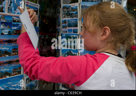 Junges Mädchen Blick auf Postkarten auf einem Display in Chamonix Mont Blanc, Frankreich. Stockfoto