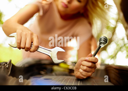 Nahaufnahme des weiblichen Hand mit Schraubenschlüssel Überprüfung Motor Autos Stockfoto
