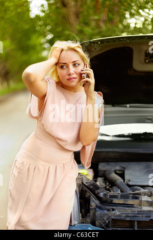 Foto von blonden Frau in Schwierigkeiten durch ihr Auto stehen und reden über Handy Stockfoto