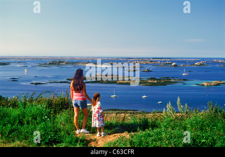 Mutter und Tochter stehen auf bluff mit Blick auf kleinen Inseln und Segelboote Bretagne Küste Bretagne in Nordfrankreich. Stockfoto