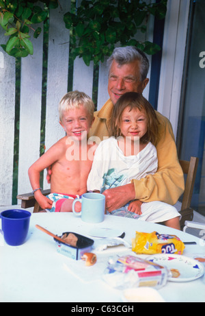 Glücklicher Vater mit Sohn und Tochter mit verschlafenen Morgen schauen über Frühstückstisch am Sommerhaus in Schweden Stockfoto