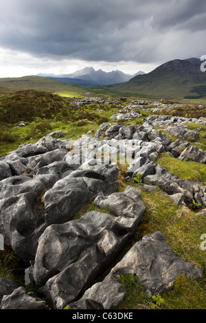 Erodiert Dolostone/Kalkstein Pflaster mit Black Cuillin Berge in der Ferne, Strath Suardal in der Nähe von Broadford, Isle of Skye, Schottland, Großbritannien. Stockfoto