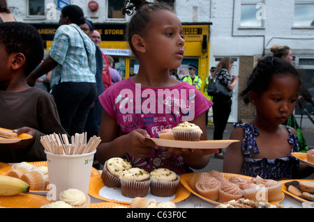 Clarence Straße Hackney. Straßenfest Tee eine Woche nach den Unruhen. Junge Mädchen Hilfe zur Selbsthilfe zu Kuchen Stockfoto