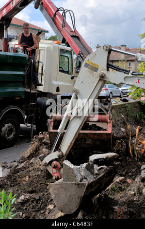 Minibagger und Eimer Schaufel Kran Bodenfreiheit von Wohn Garten zu tun. Vorbereitung für den Einbau. Stockfoto