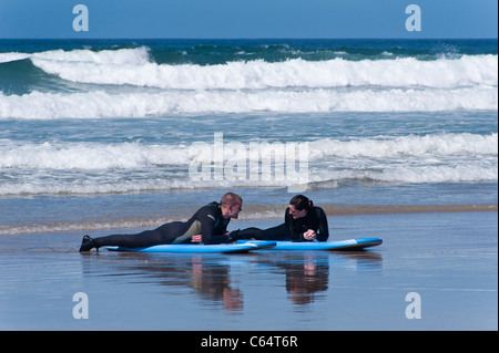 Wenige Männer und Frauen tragen Anzüge, plaudern und entspannen auf ihren Surfbrettern nach dem Surfen im Meer Stockfoto