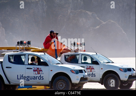 RNLI Freiwilligen Strand Rettungsschwimmer an Perranporth, einem beliebten Urlaubsort an der Küste in Cornwall UK, sitzen an einem Fahrzeug Stockfoto