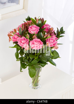 Bouquet von rosa Rosen und Alstroemeria in einer Vase von einem Fenster Stockfoto