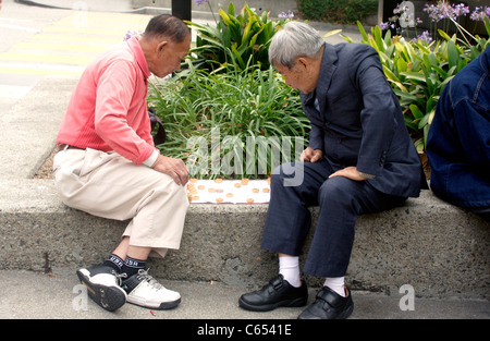 Zwei hochrangige chinesische Männer spielen Sie Mahjong in einem Park in Chinatown, San Francisco Stockfoto