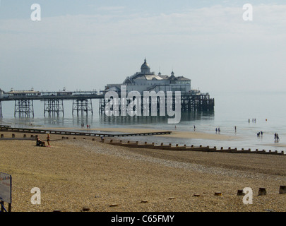 Eastbourne Strand mit Badesteg im Hintergrund, die Flut ist auf dem Weg nach draußen und Menschen sind im Meer planschen. Hellen Morgen Stockfoto